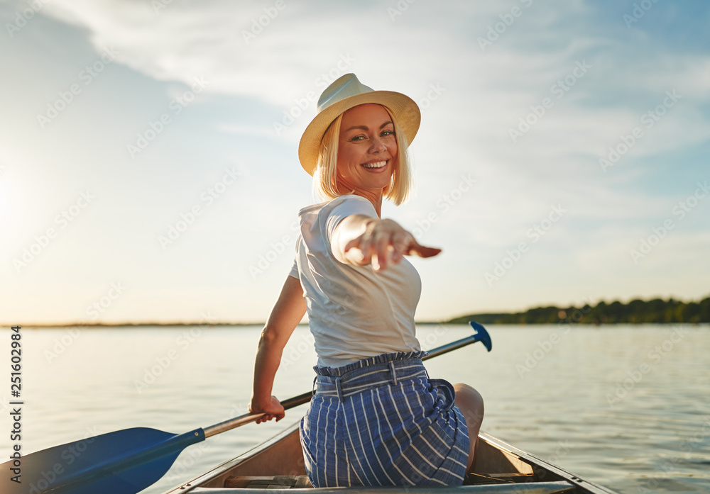 微笑的年轻女子在阳光明媚的夏天划独木舟