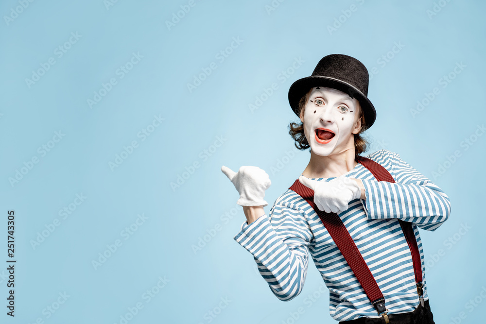 Emotional pantomime with white facial makeup showing empty space on the blue background, advertising