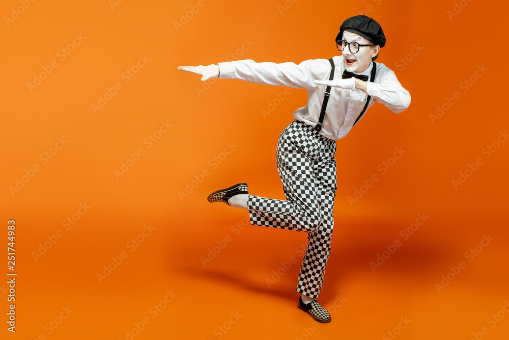 Emotional pantomime with white facial makeup showing empty space on the orange background, advertisi
