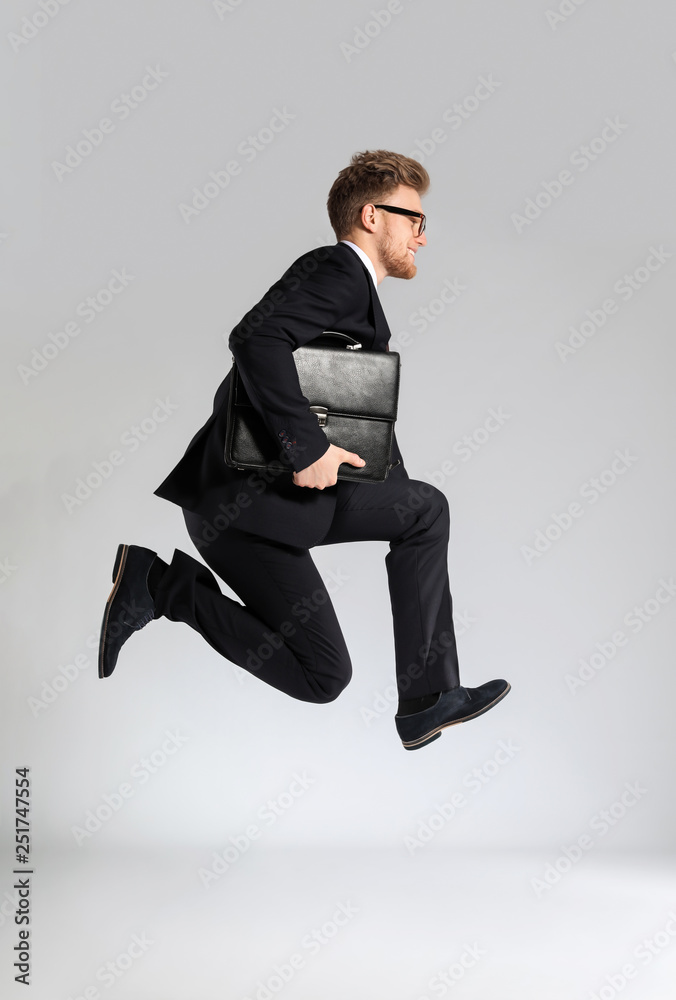 跳跃的商人，浅色背景下带着时尚的公文包