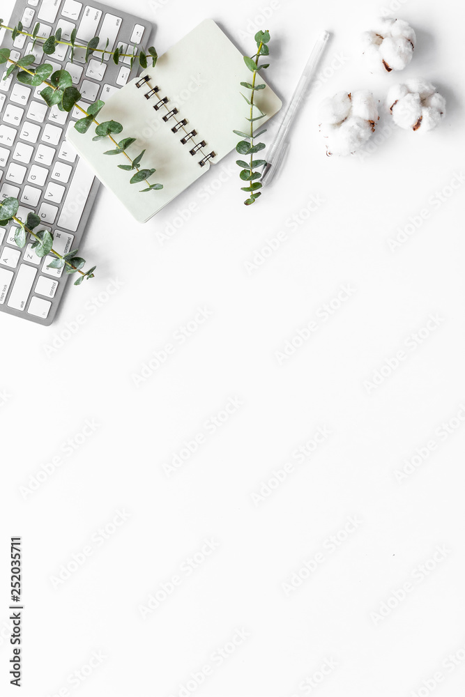 笔记本电脑，白色桌子上的棉质树枝平放着复制空间。最小的自由职业者家庭办公桌工作
