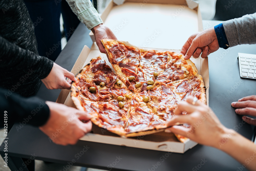 Close-up image of businesspeople sharing pizza.