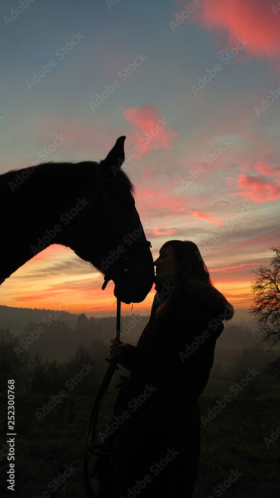 特写：日出时，一位年轻女子站在离木马很近的地方，这是一张可爱的照片。