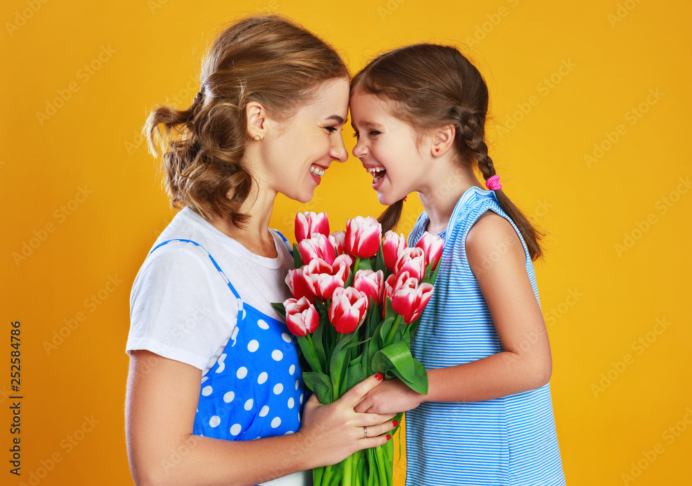 happy mothers day! child daughter   gives mother a bouquet of flowers on color yellow background.