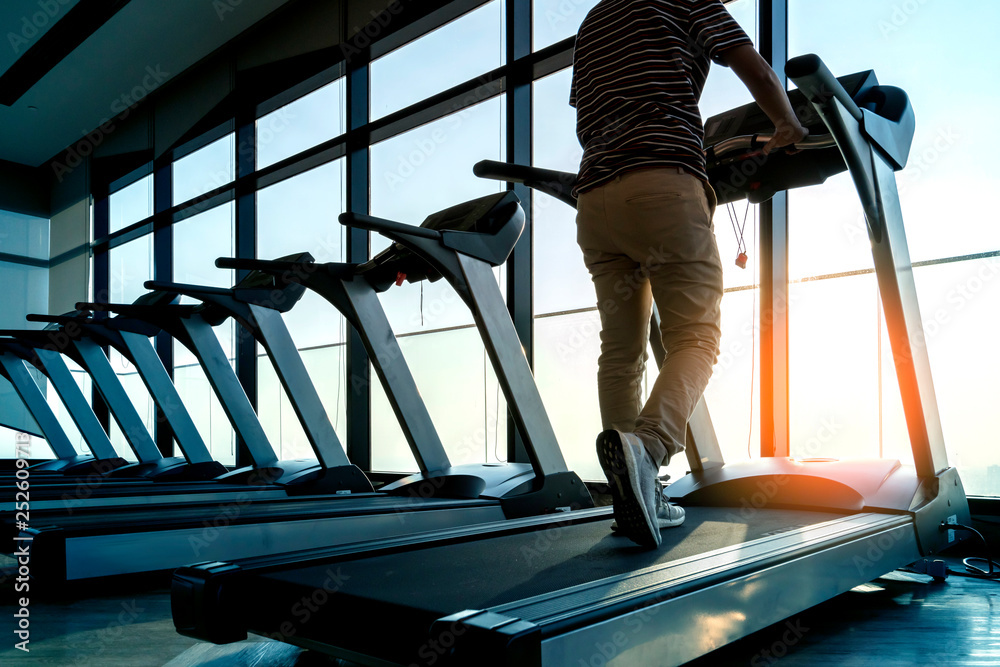 跑步机排在健身馆里，有窗户和日落背景