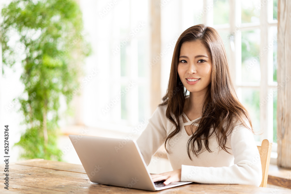 漂亮的亚洲女人在客厅里用笔记本电脑