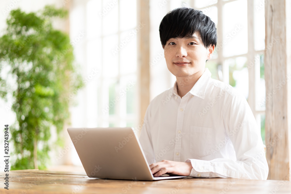 亚洲年轻男子在客厅使用笔记本电脑