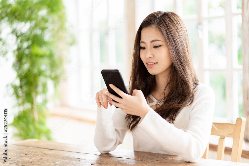 attractive asian woman using smart phone in living room