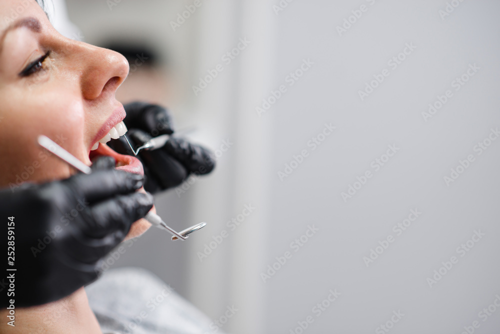 女性患者的侧视图，口腔张开，牙医的手拿着牙科器械，复印水疗中心