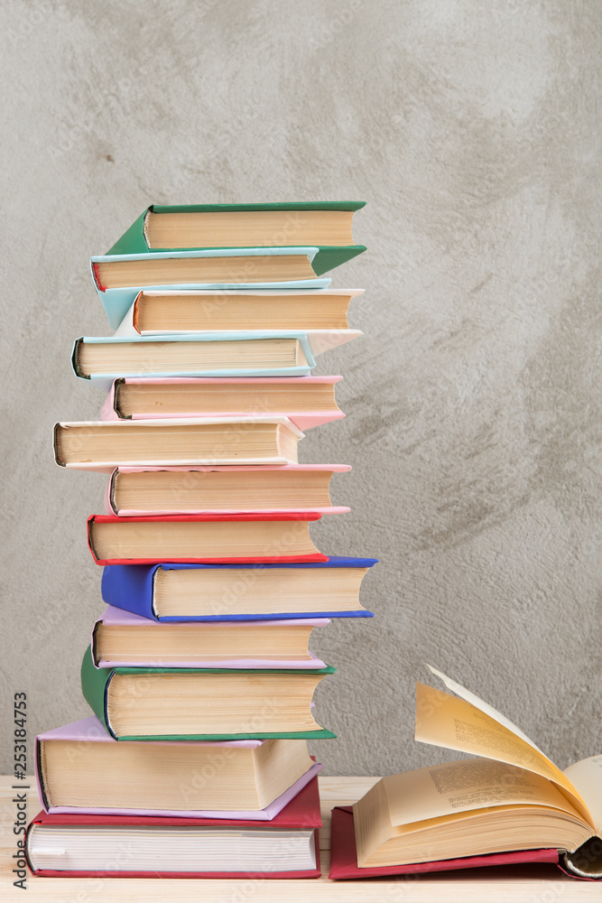 教育与阅读理念——木桌上的一组五颜六色的书，混凝土墙黑板