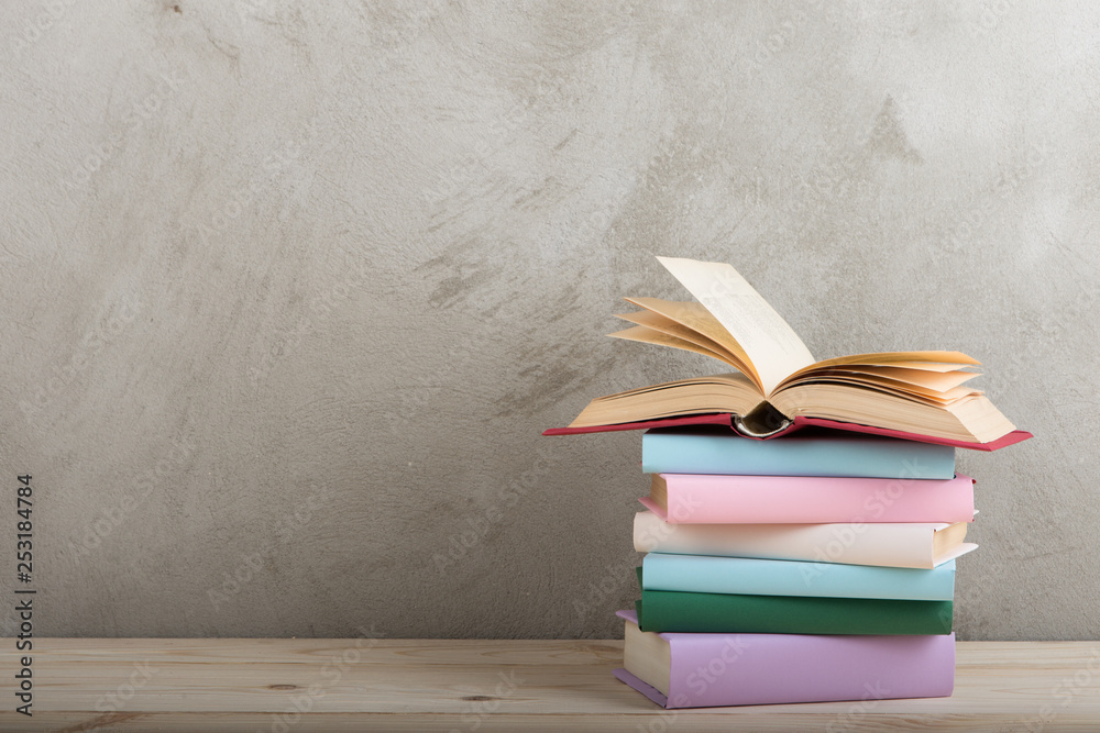 教育和阅读理念——木桌上的一组五颜六色的书，混凝土墙黑板