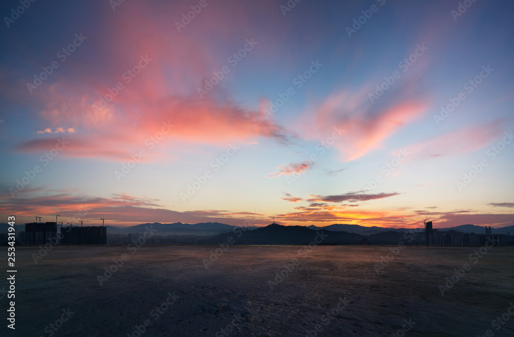 空旷的混凝土水泥地面，伴随着引人注目的日出，紫色和粉红色的天空。