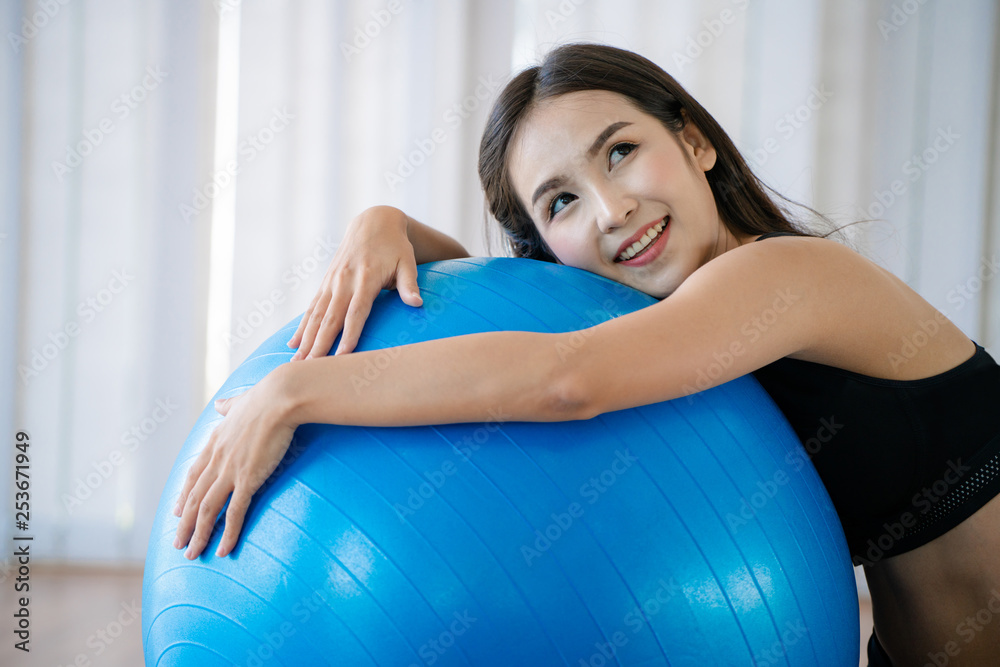 健身中心的漂亮年轻女子用健身球做普拉提运动。健康的生活方式