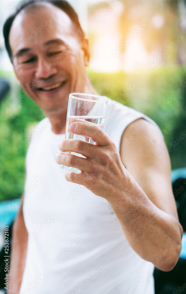 老年人运动后在健身房健身中心喝矿泉水。老年人健康的生活方式。