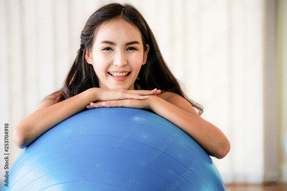 健身中心的漂亮年轻女子用健身球做普拉提运动。健康的生活方式