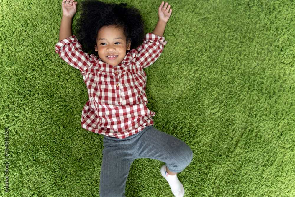 快乐的孩子们，孩子们微笑着躺在家里客厅的绿色地毯上。