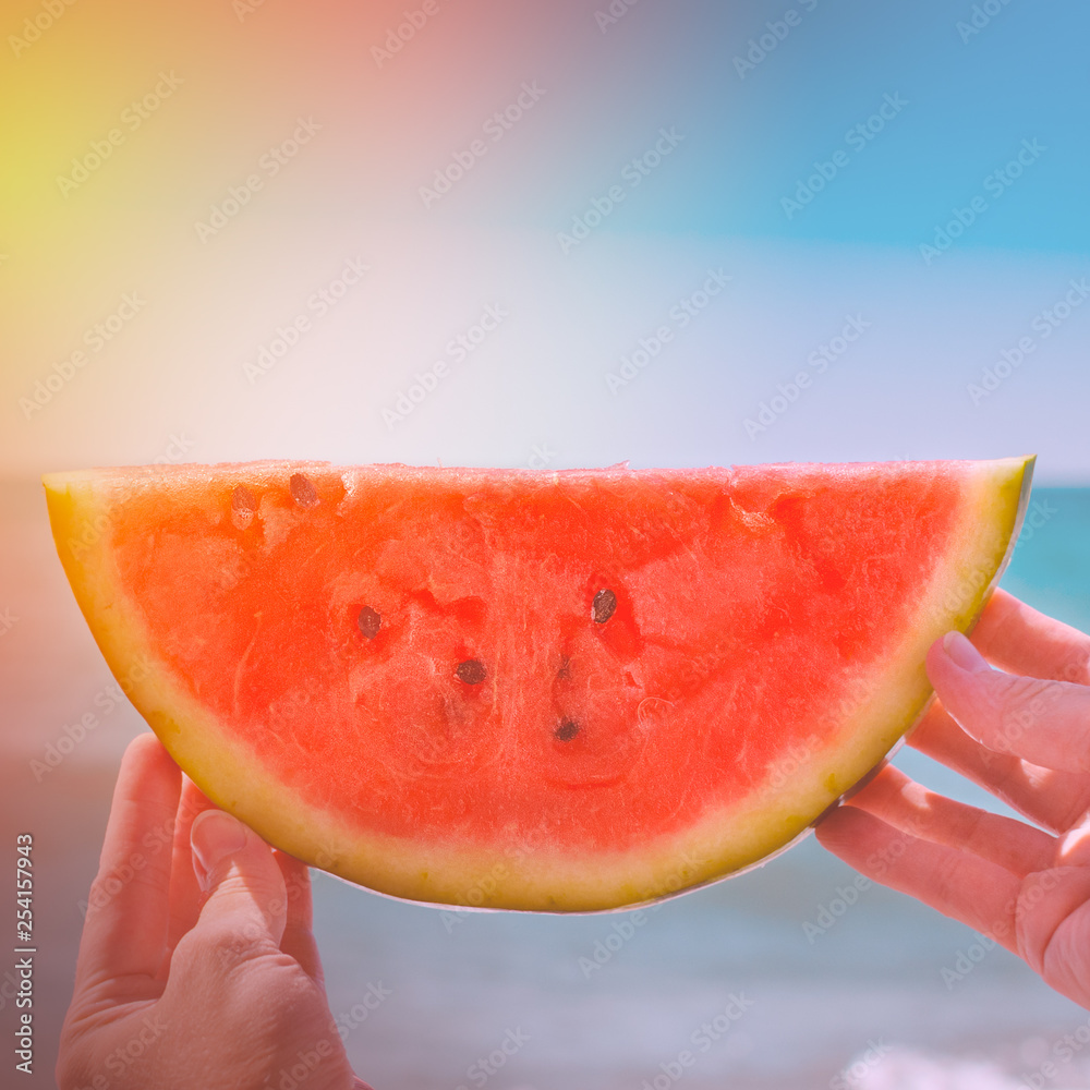 Watermelon, juicy slice in the hands of a woman with over the sea, in the rays of a sunny sunset. Di