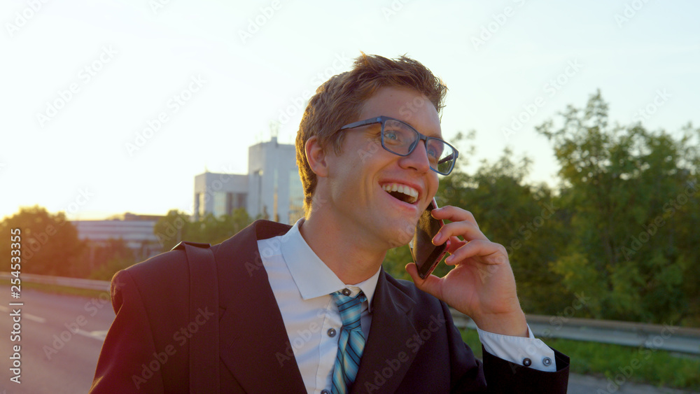 CLOSE UP: Businessman laughs while talking on his cell phone on his way to work.