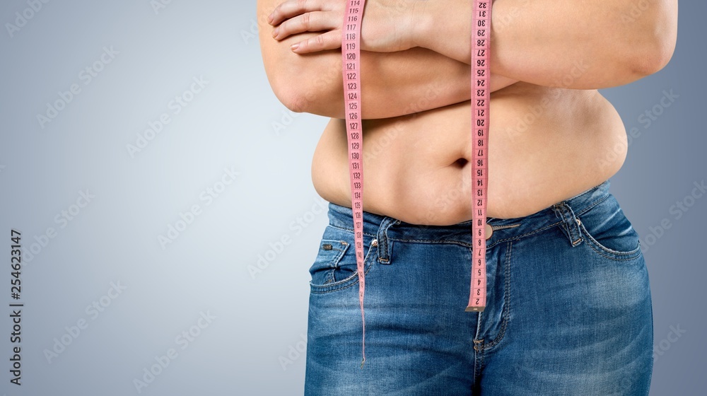 超重，胖女人在后台测量她的肚子