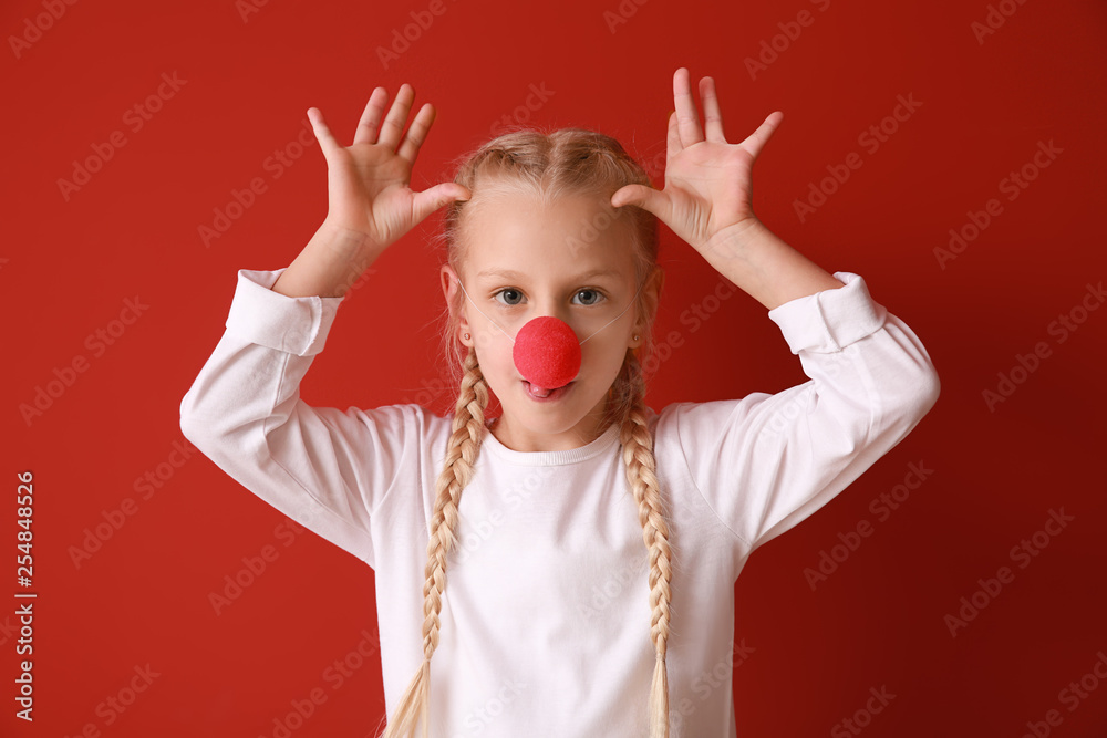 有趣的小女孩，彩色背景上有小丑鼻子。愚人节庆祝活动