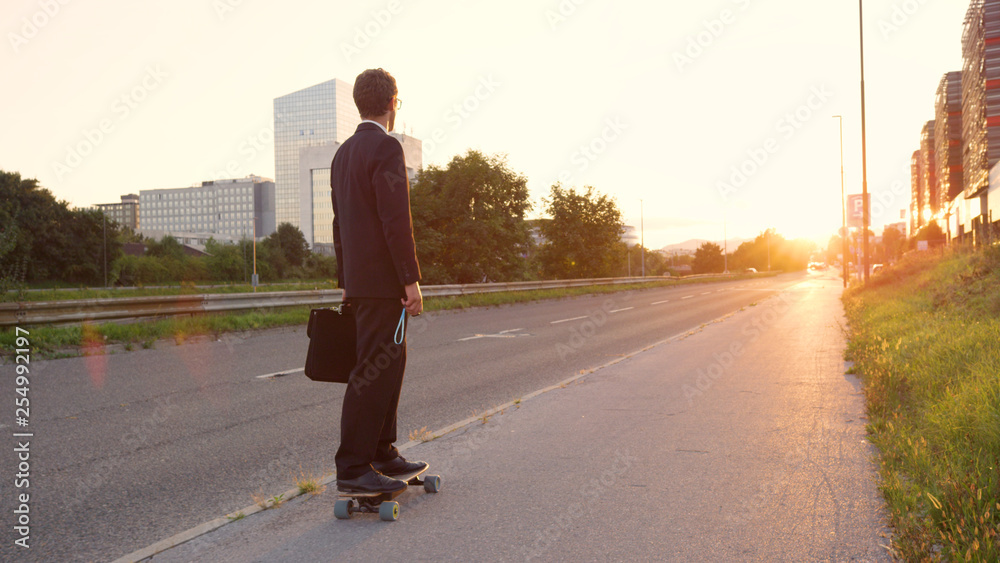 LENS FLARE：活跃的商人骑着他的长板在阳光明媚的街道上巡游。