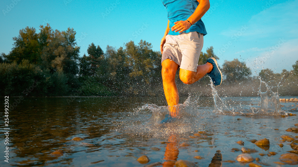 低角度：运动员在河岸慢跑的酷镜头。