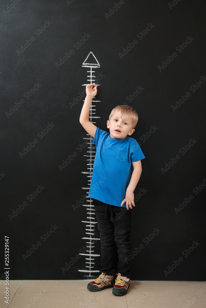 小男孩在黑暗的墙壁附近测量高度
