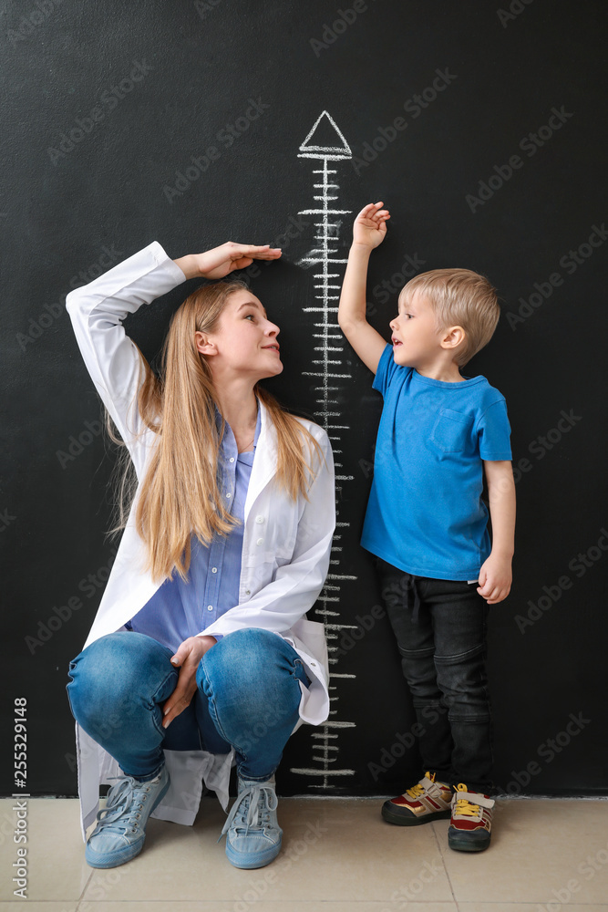 女医生带着小男孩在暗墙附近测量身高