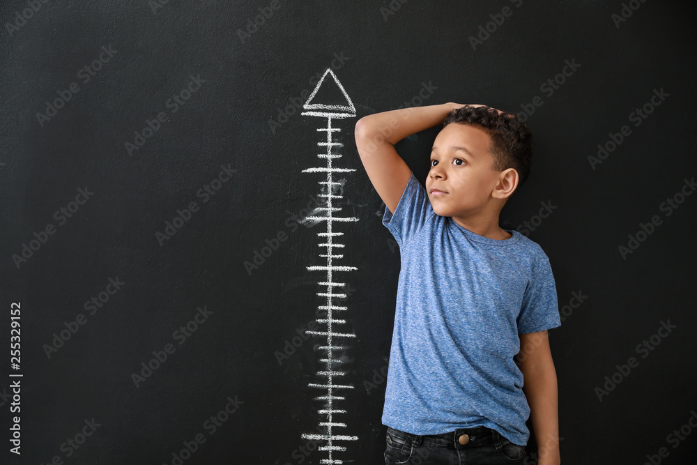 非裔美国男孩在暗墙附近测量身高