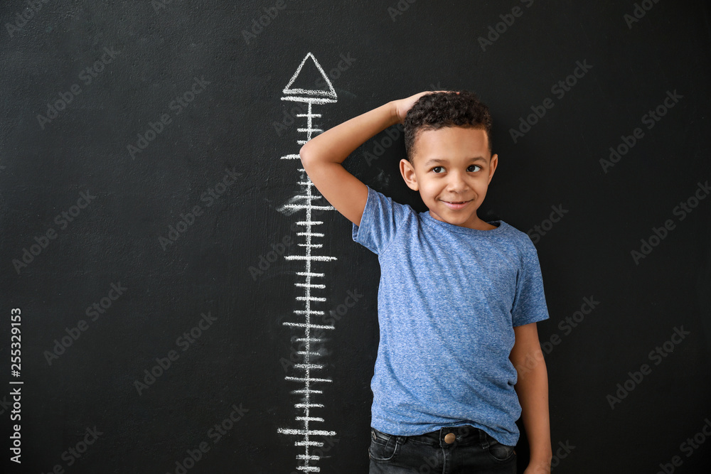非裔美国男孩在暗墙附近测量身高