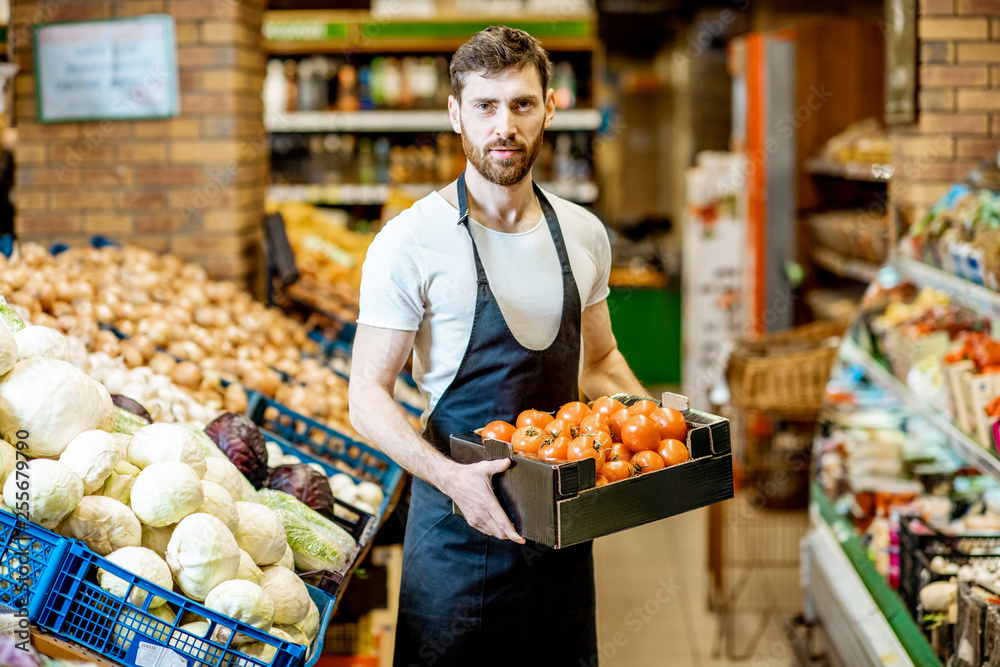 一位英俊的店员或农民的肖像，手里拿着一个装着新鲜西红柿的盒子