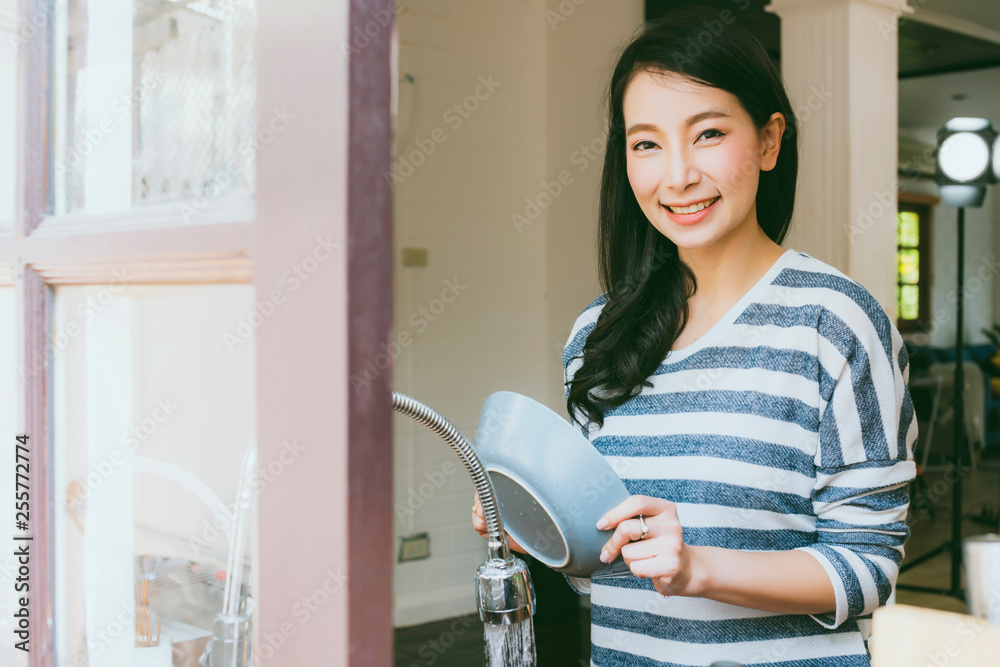 迷人美丽的家庭主妇亚洲女人在厨房家庭中微笑快乐地洗碗