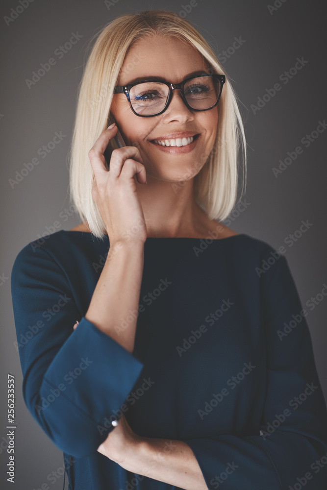 微笑的女商人对着一个灰色的ba用手机说话