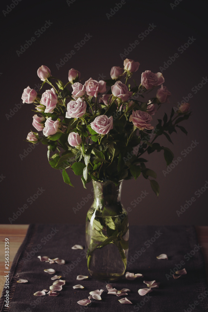 深色背景下桌上摆放着美丽玫瑰的花瓶