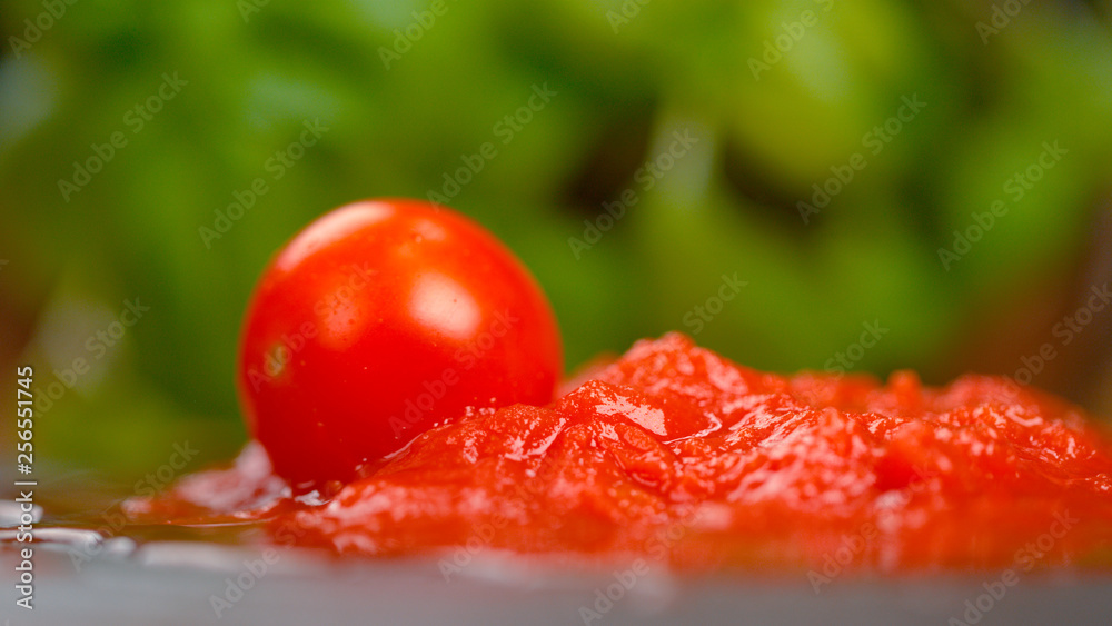 MACRO：成熟的圆形番茄掉进桌子上的一滩卤汁里。
