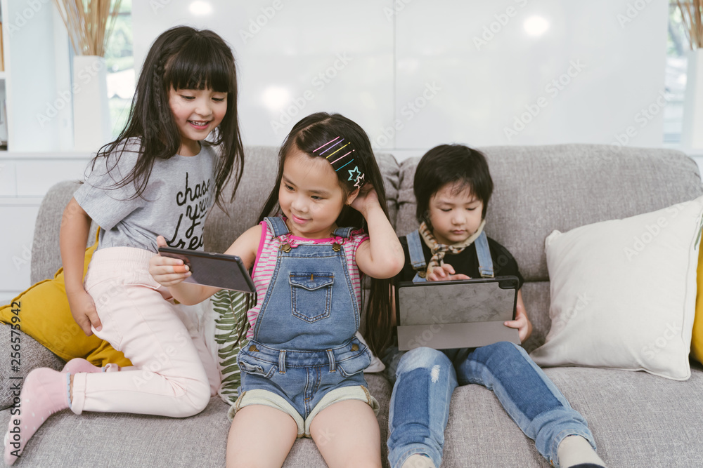 一群小孩子一起在数字平板电脑和手机上看电影、电影和动画片。孩子们在玩