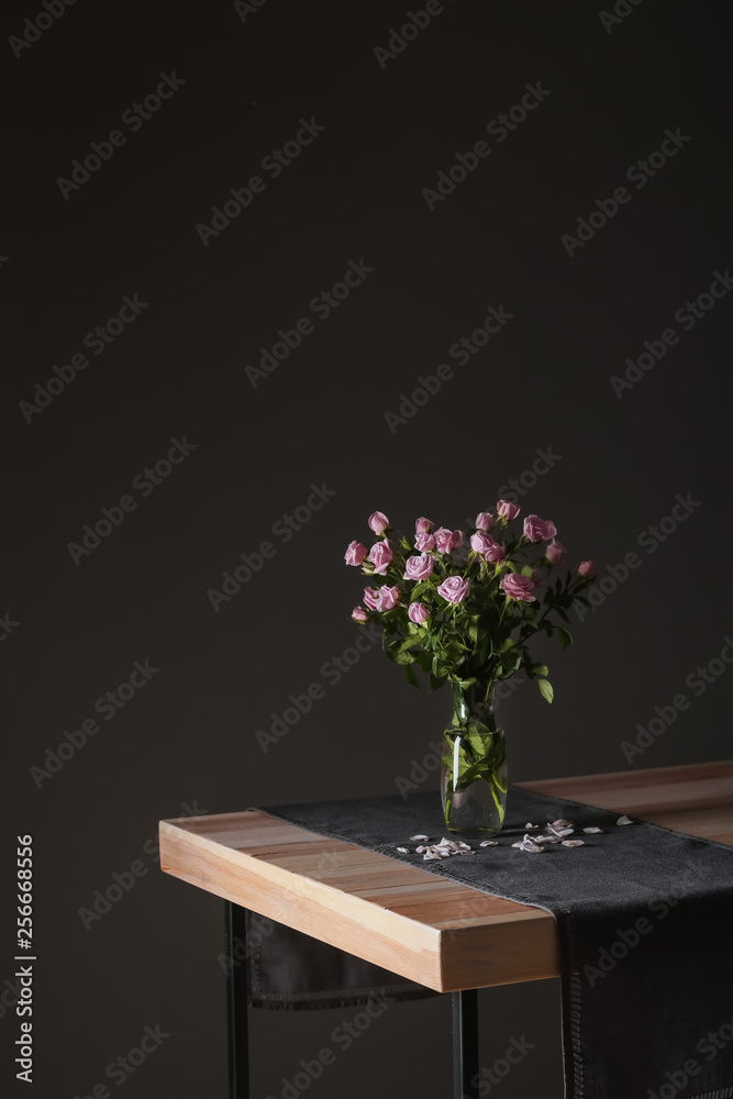深色背景下桌上摆放着美丽玫瑰的花瓶