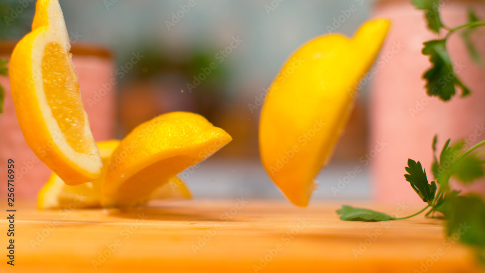 MACRO，DOF：新鲜的四分柠檬掉到厨房的木制桌子上。