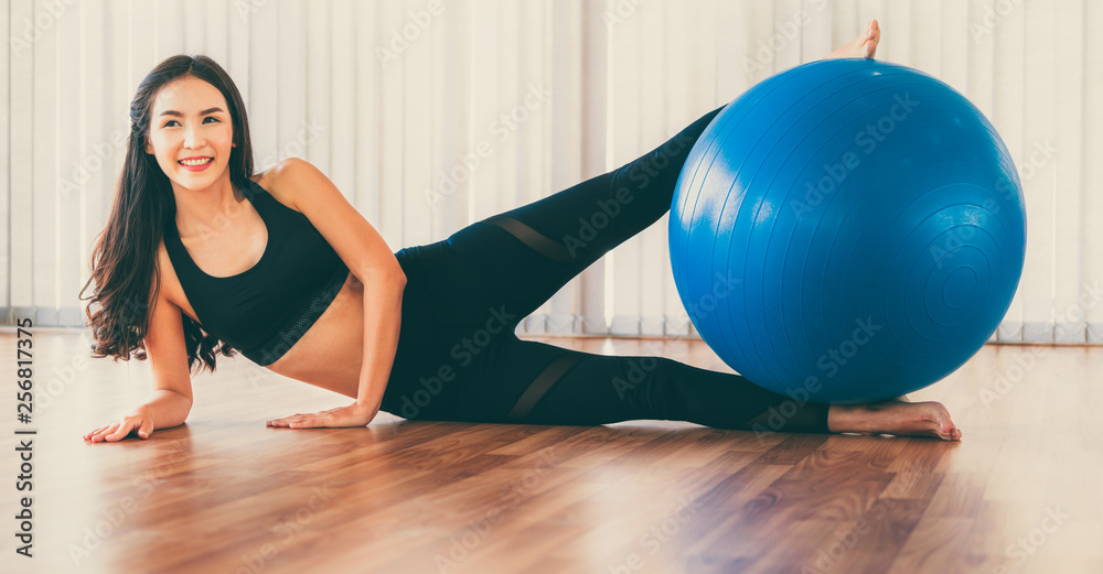 Beautiful young woman in fitness center doing pilates exercise with fitness ball. Healthy lifestyle 
