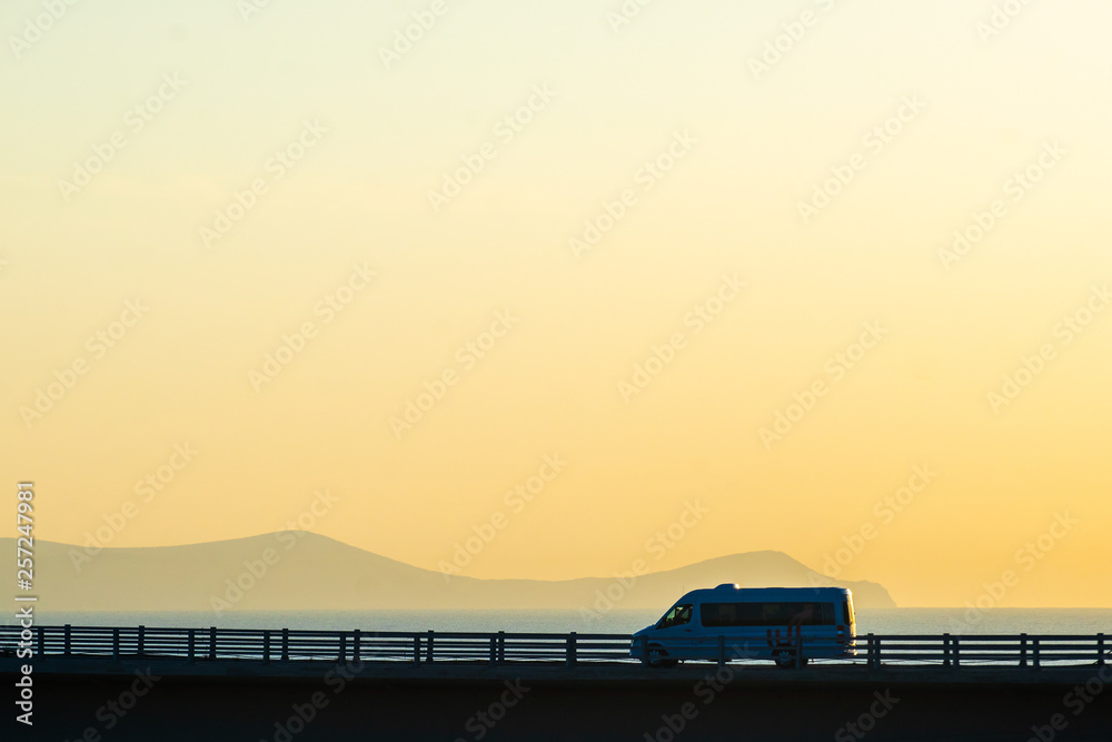 黎明时分，在群山和大海的背景下，公路桥上的汽车