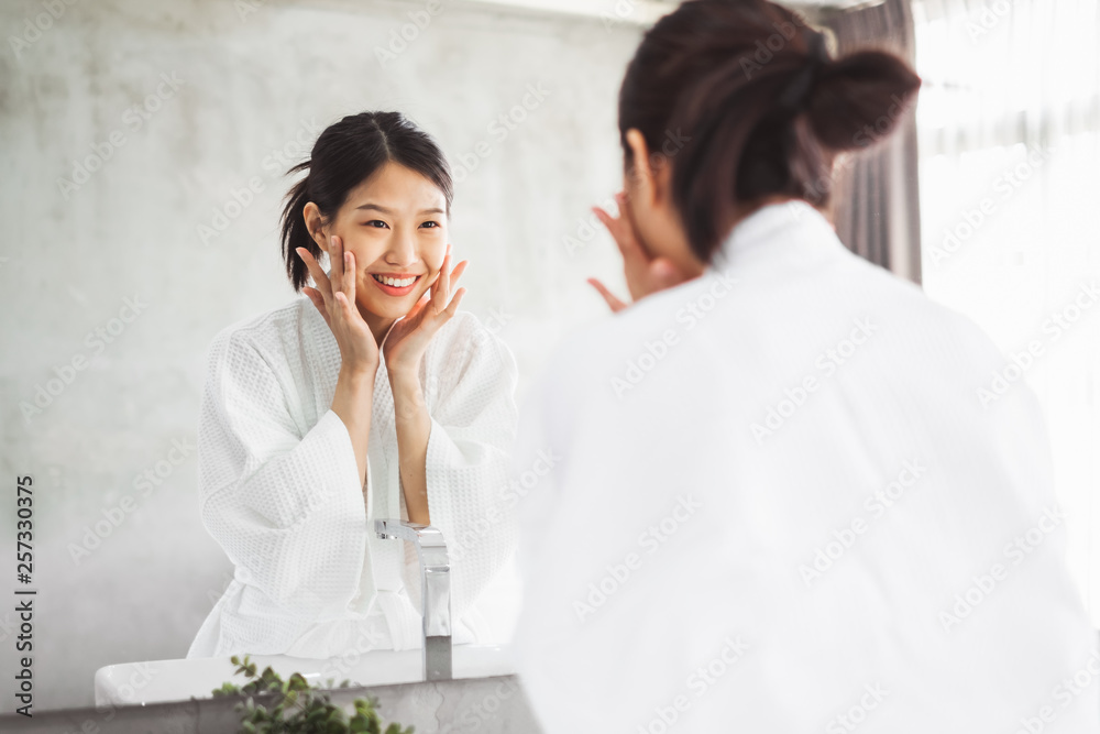 亚洲女性在镜子前清洁面部，护肤和化妆品去除概念