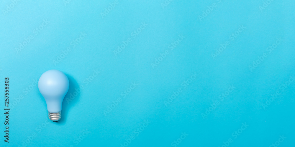 Colored light bulb on a blue paper background