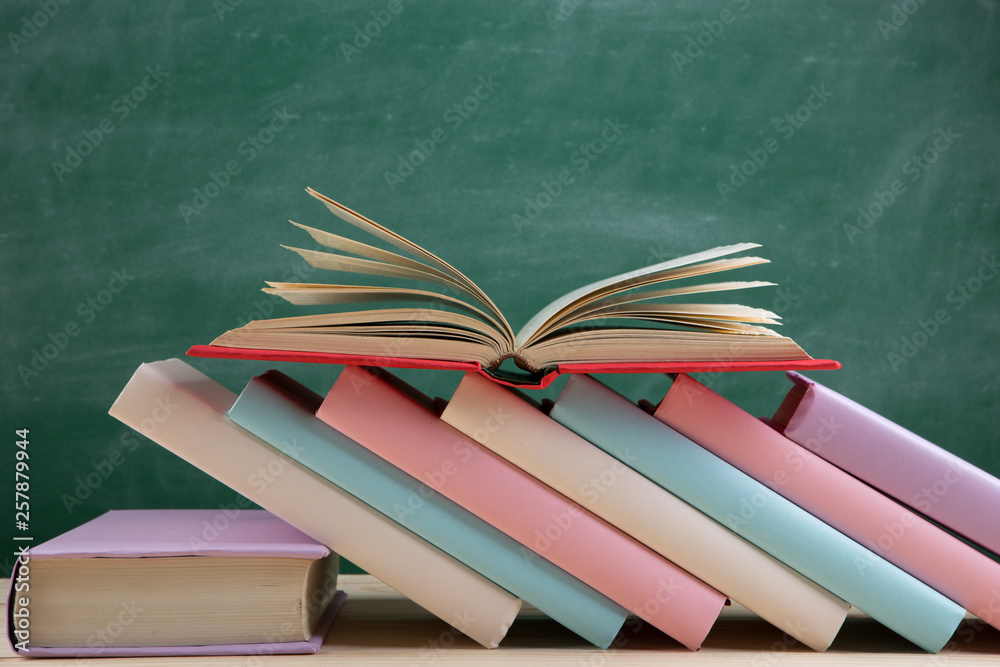 教育和阅读理念——教室木桌上的一组五颜六色的书，黑板