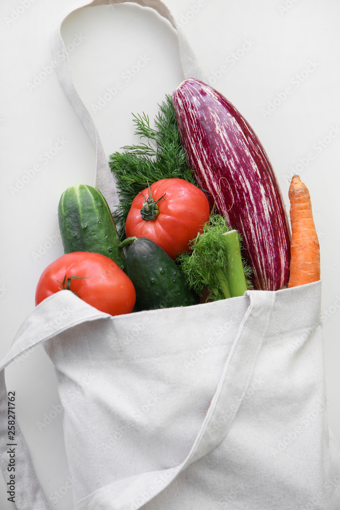 Eco bag with fresh vegetables on white background