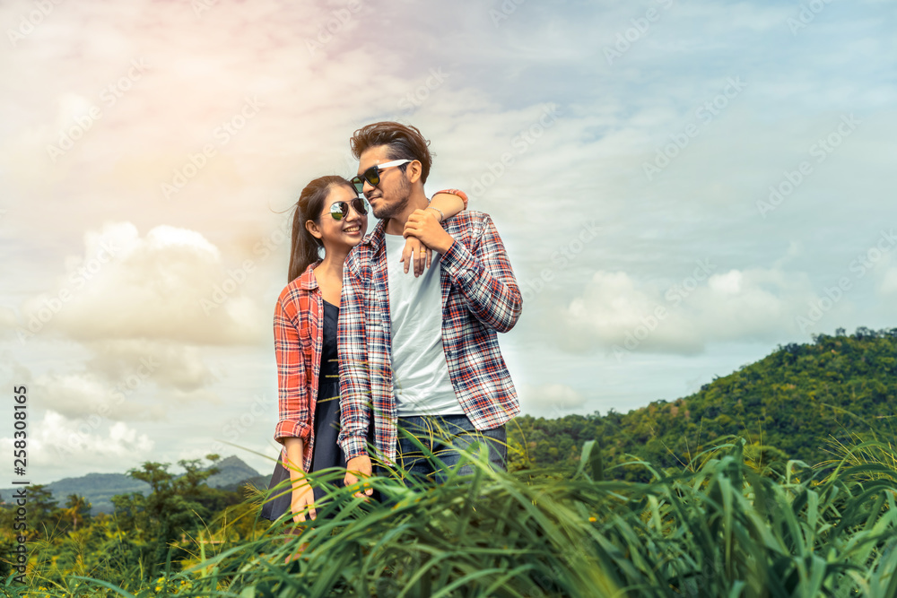Happy couple take a romantic walk in green grass field on the hills. Travel and honeymoon concept.
