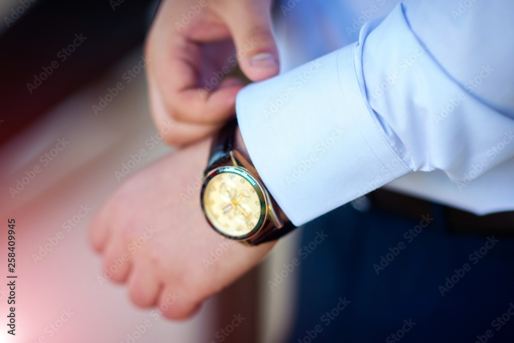 商人在手表上检查时间，男人在手边放时钟。新郎在准备
