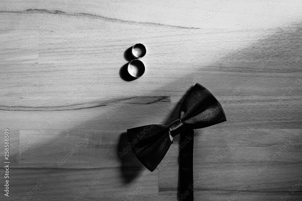 黑色领结和结婚戒指以数字8的形式躺在木制背景上。婚礼ac