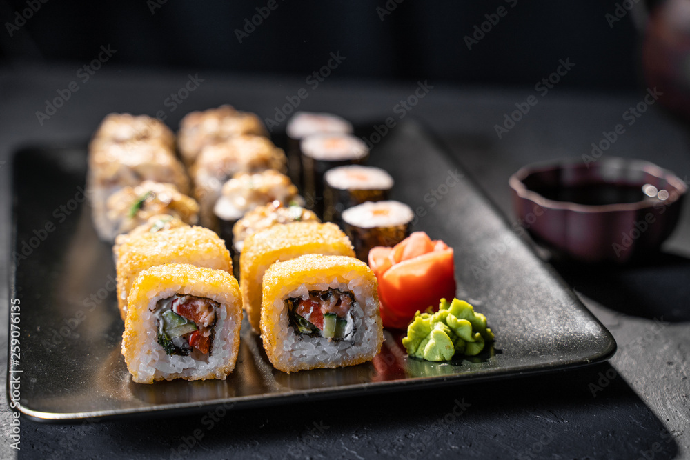 美味的寿司卷用筷子夹在黑色桌子上