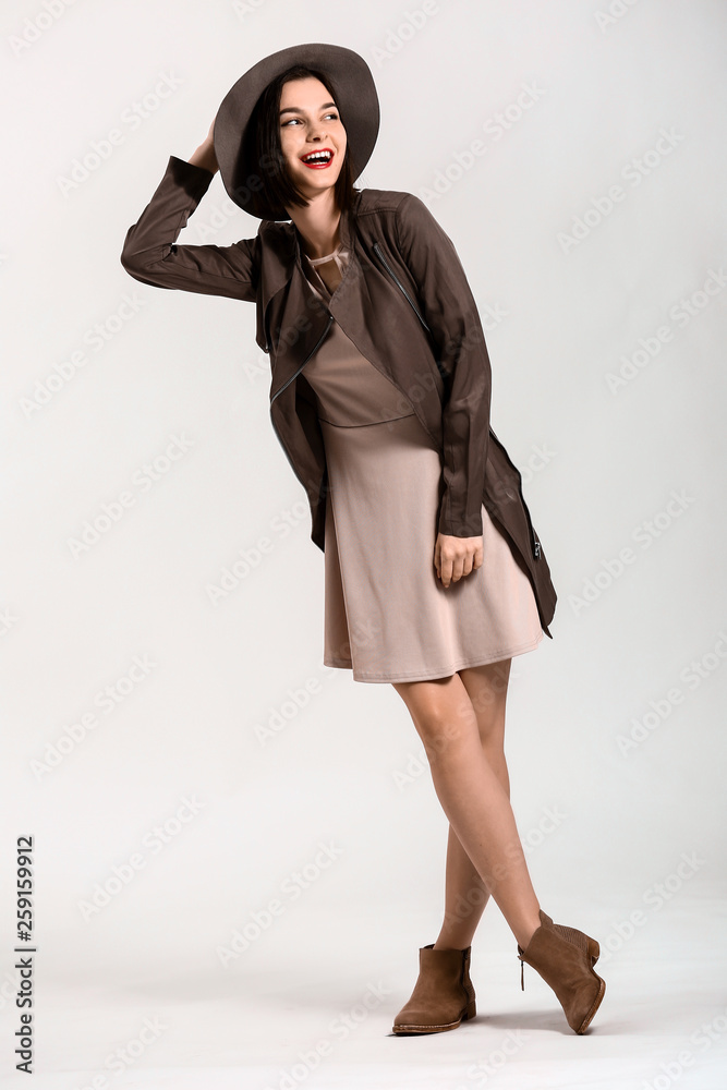 Beautiful young woman in modern stylish clothes on light background