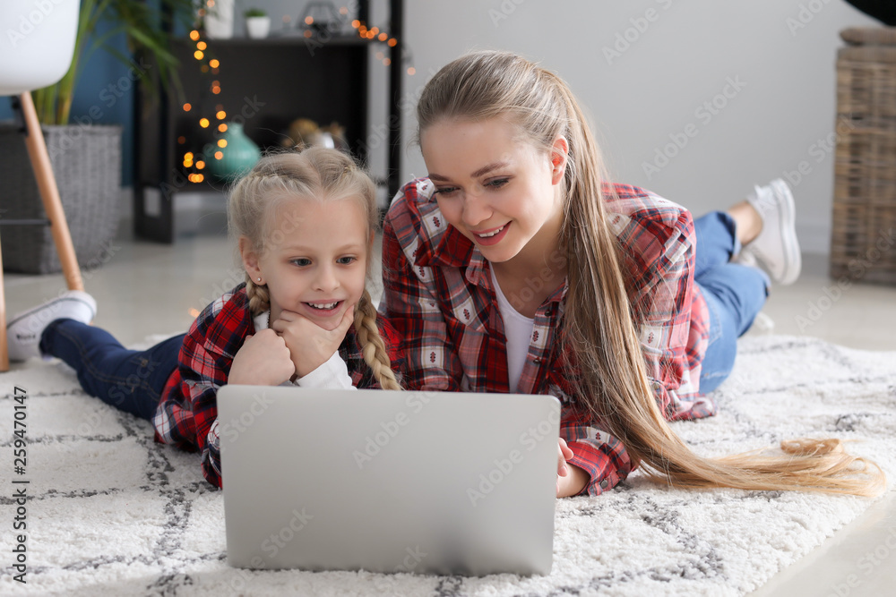 年轻的母亲带着小女儿在家看动画片